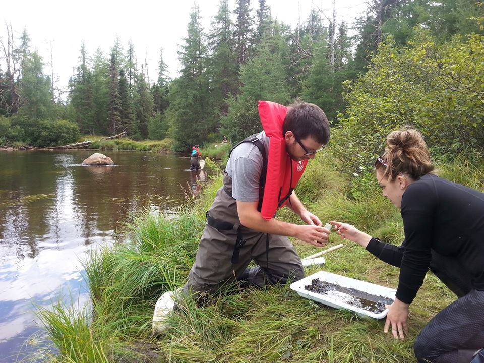 two students conducting research by riverbed