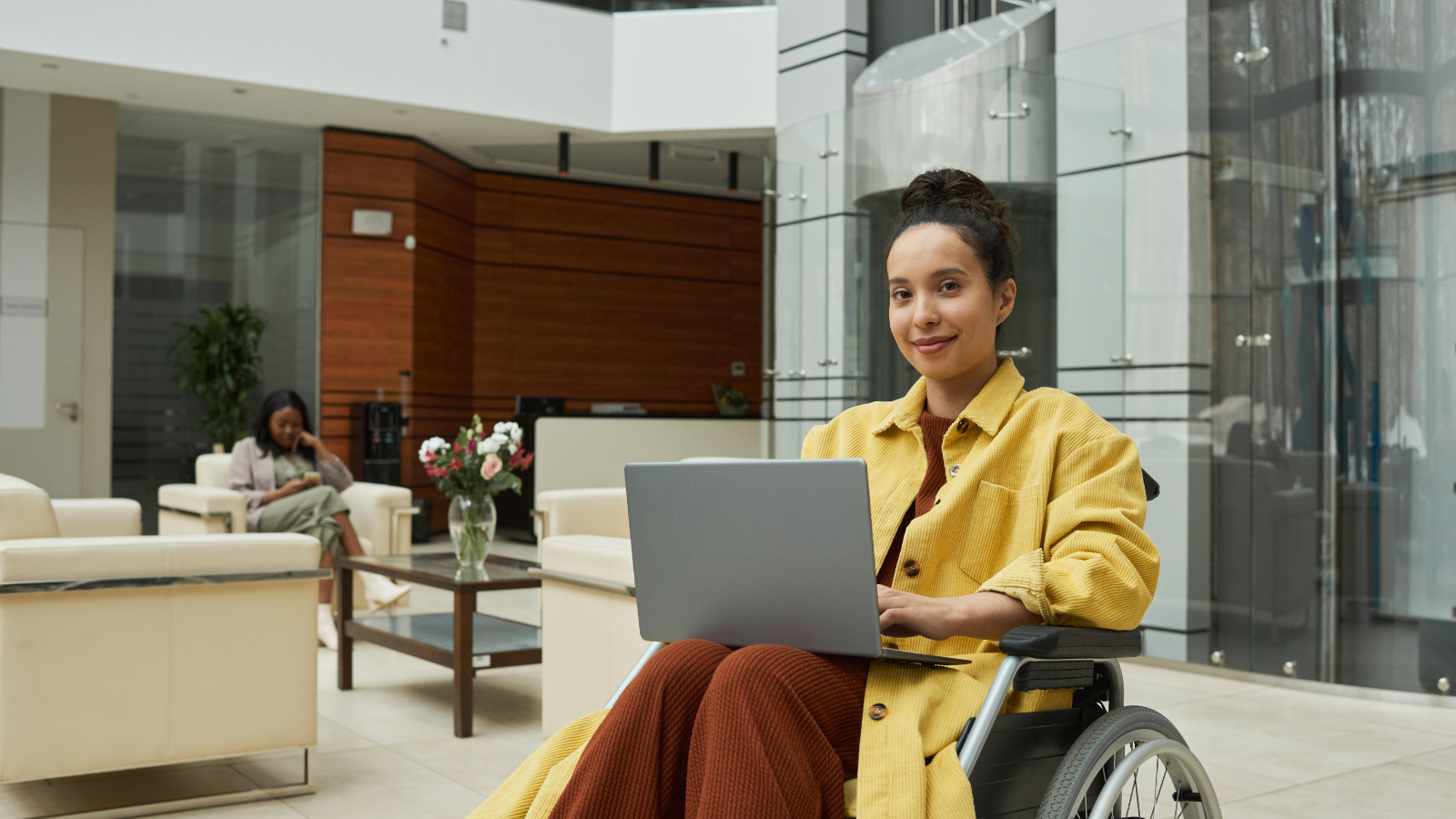 woman in wheelchair in an office building on a computer.