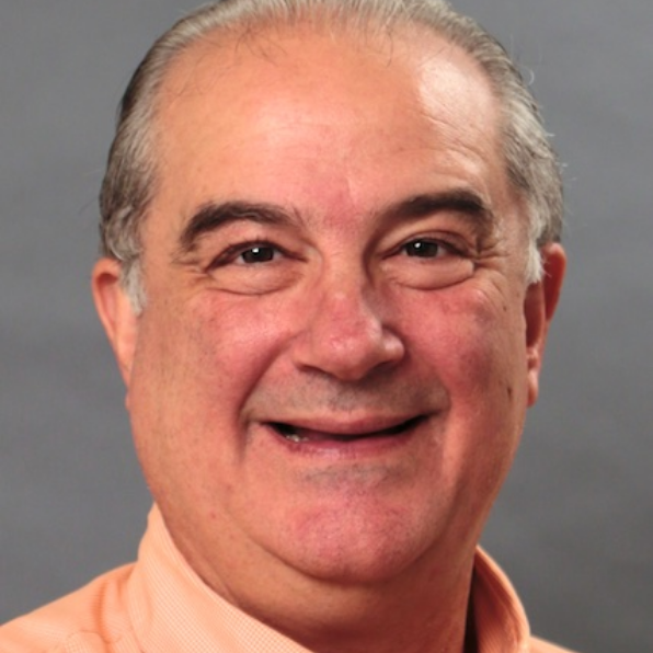 Headshot of Dr. Fabio Milner in front of a grey background wearing a light orange button-up shirt