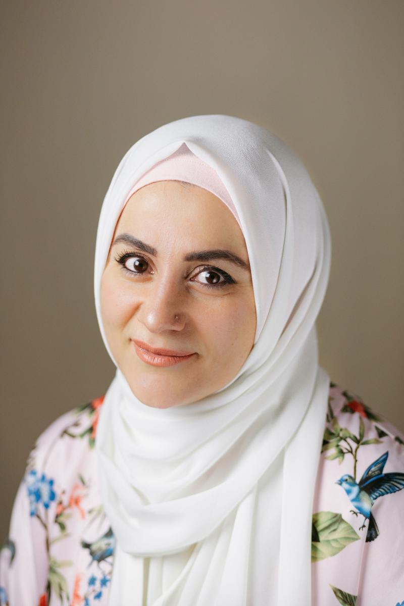Headshot of Ally Hamie, wearing a white hijab and a floral shirt