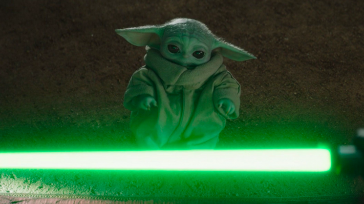 baby yoda in front of light saber