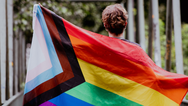 person holding inclusive LGBTQ flag