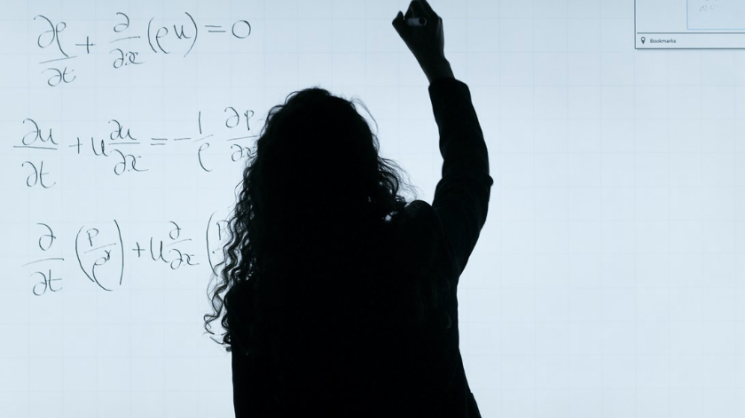 silhouette of a woman writing math equations on a whiteboard