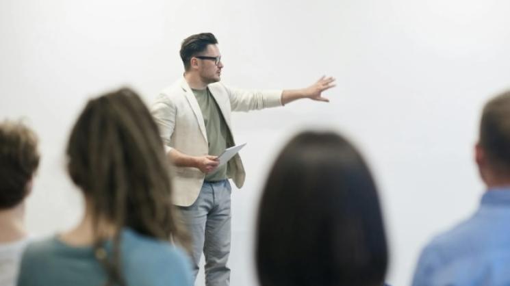 professor teaching students; pointing at whiteboard