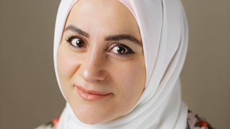 Headshot of Ally Hamie, wearing a white hijab and a floral shirt